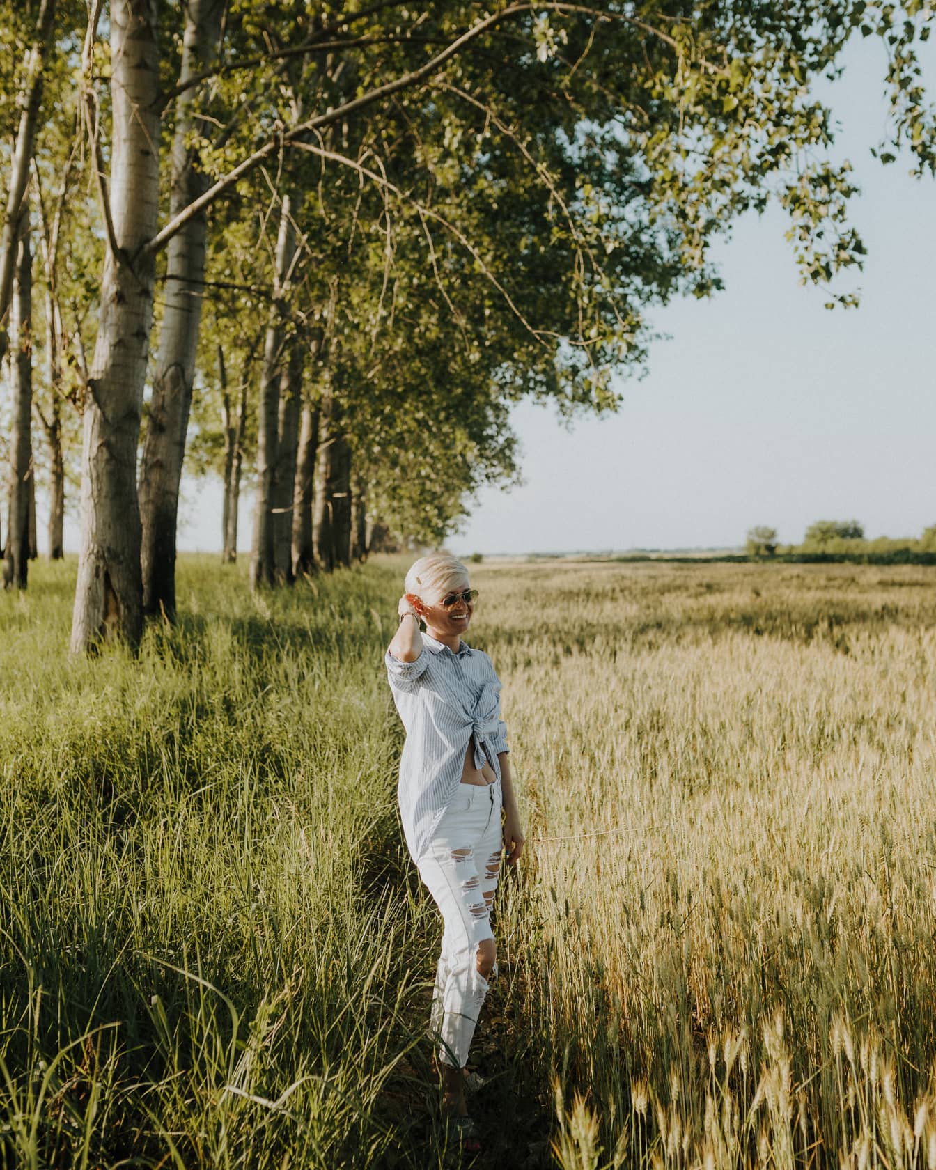 Short hair blonde in casual white trouser pant smiling in wheat field