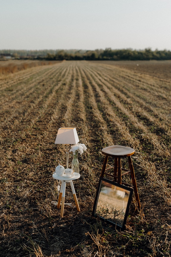 Rustikaler Stuhl aus Holz mit Spiegel und weißer Lampe im Feld
