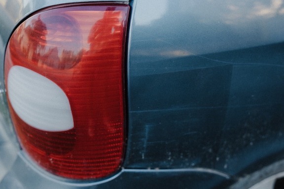 Plastik merah tua jika lampu belakang mobil sedan biru close-up