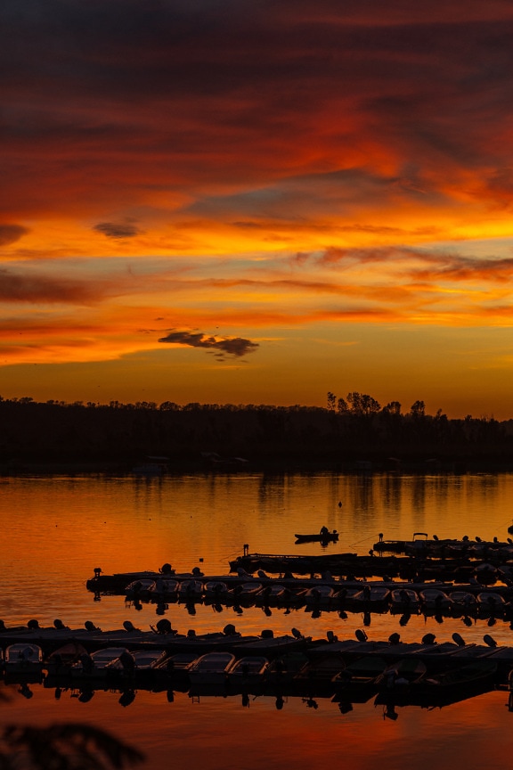 Majestætisk panorama ved søen med mørkerød solnedgang