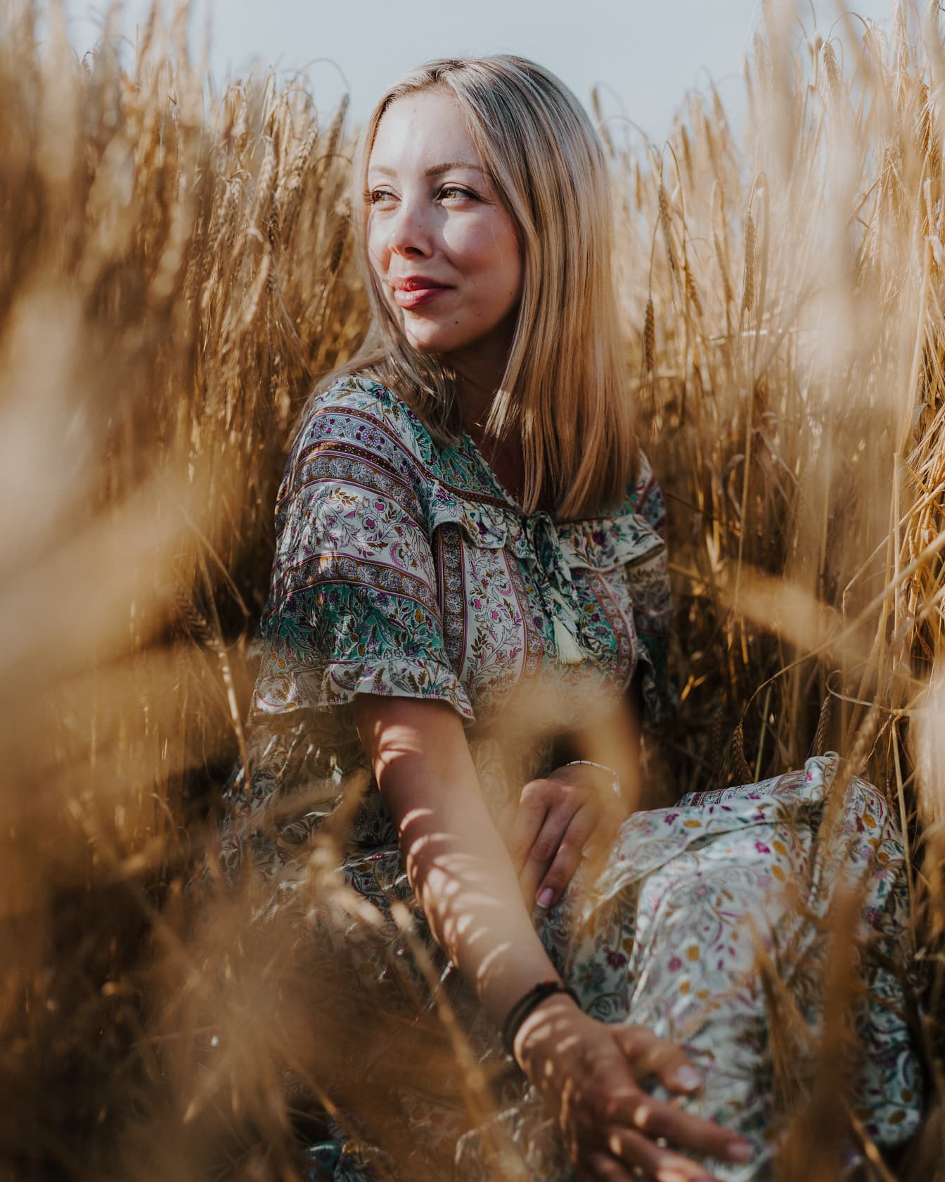 Ursnygg blondin som sitter i vetefält majestätiskt fotografi