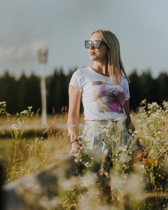 Young woman teenager posing in meadow on bright summer day
