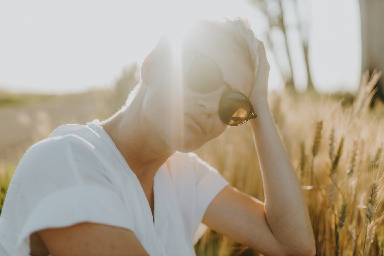 Retrato de cabelo curto loiro com óculos de sol em dia ensolarado brilhante