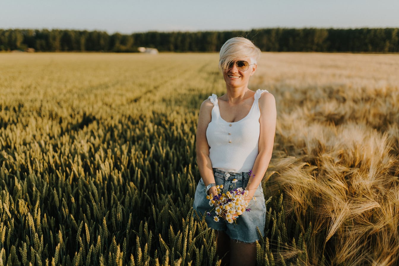 Šťastná nádherná žena v sračkách a džínsových šortkách na pšeničnom poli
