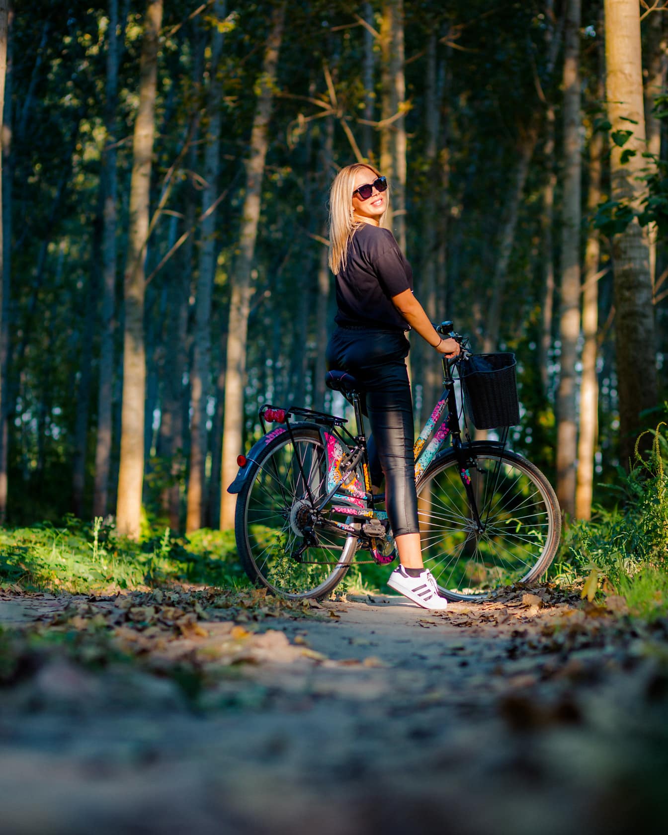 Adolescente de cabelo loiro adorável na bicicleta na floresta