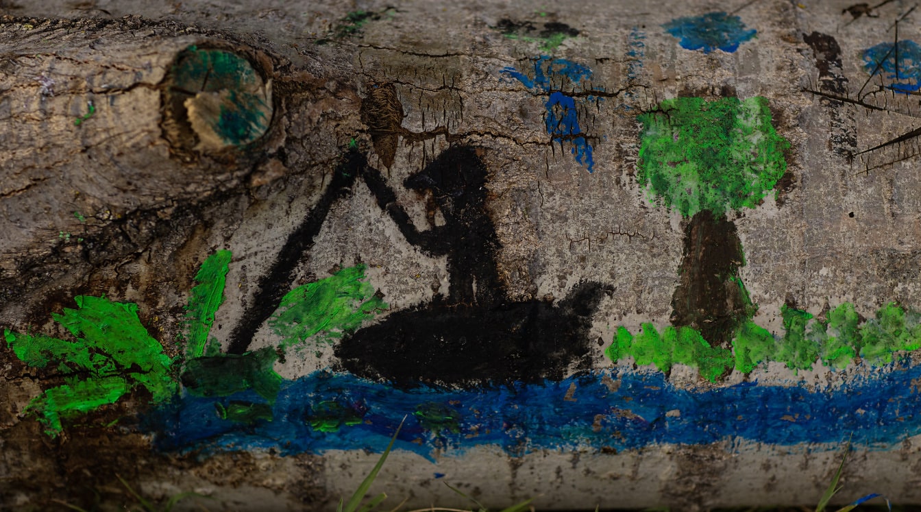 Naiivi taidegraffitipiirros puunrungon kuoresta lähikuvassa