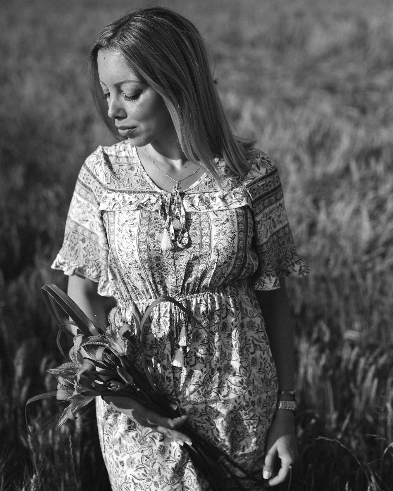 Monochromatický portrét nádherné ženy v pšeničném poli v šatech