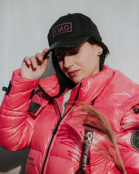 Gorgeous woman with black hat and pinkish jacket posing