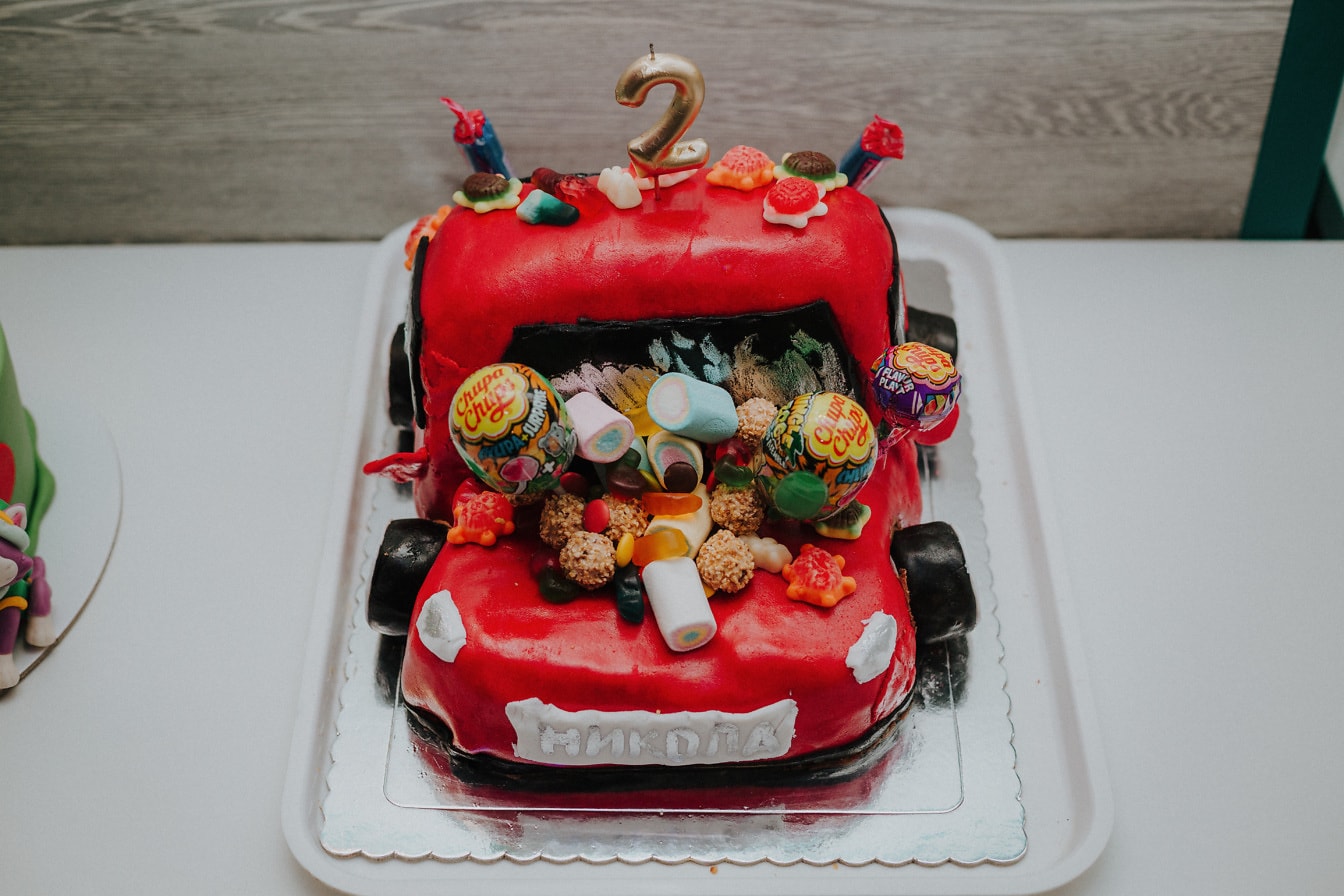 Темно-красный гоночный спортивный автомобиль с праздничным тортом и леденцами