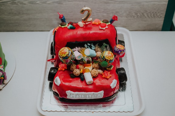 Tamnocrvena rođendanska torta u obliku sportskog automobila s lizalicama