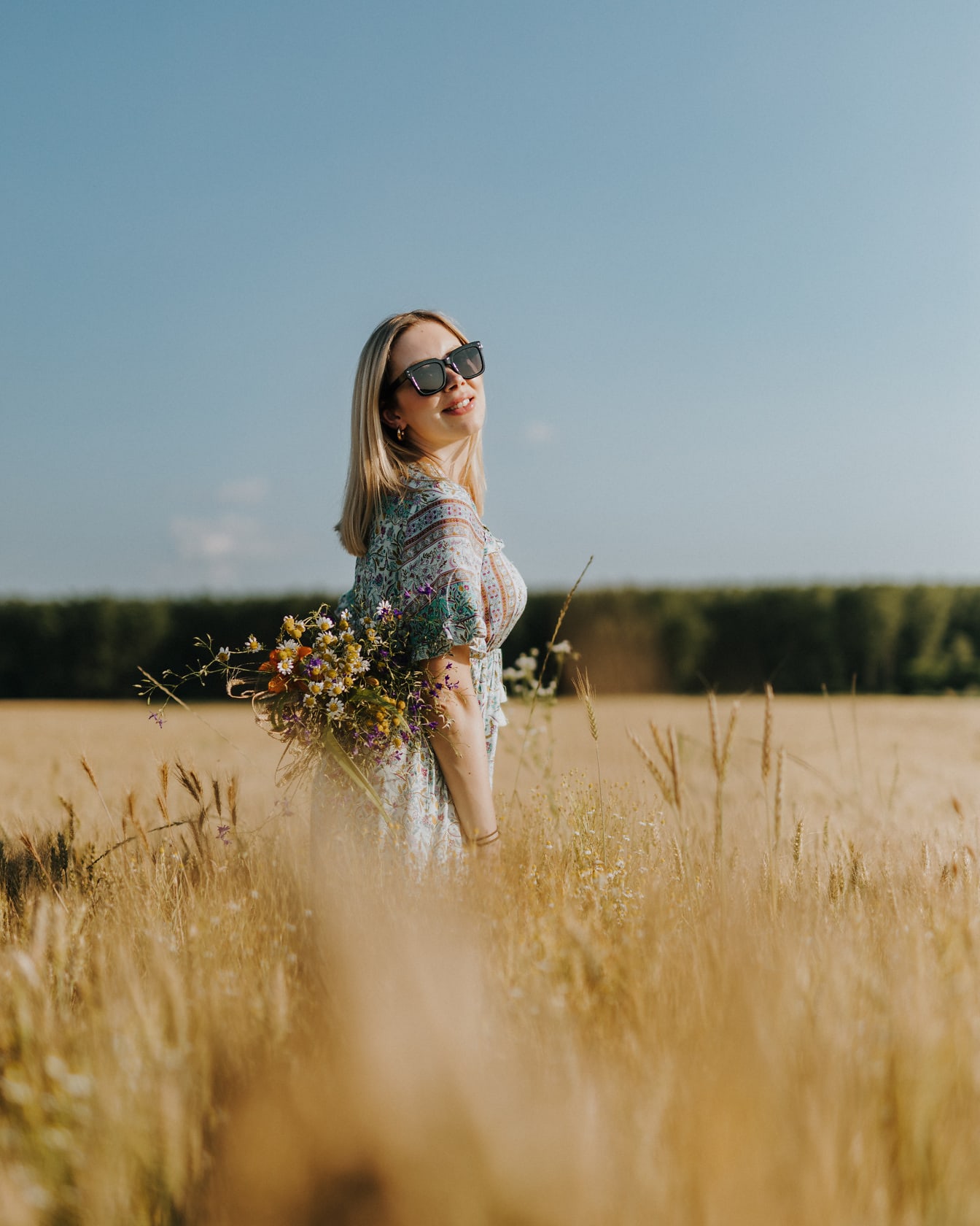 Donna sorridente dai capelli blone di bell’aspetto nel campo di grano