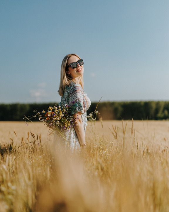 Usmívající se blone vlasy dobře vypadající žena v pšeničném poli