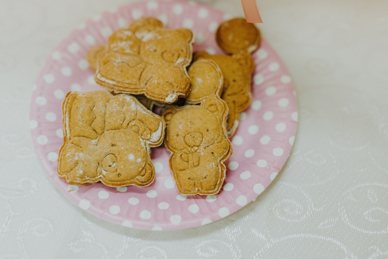 Deliciosos biscoitos da raça gengibre com açúcar no prato rosado