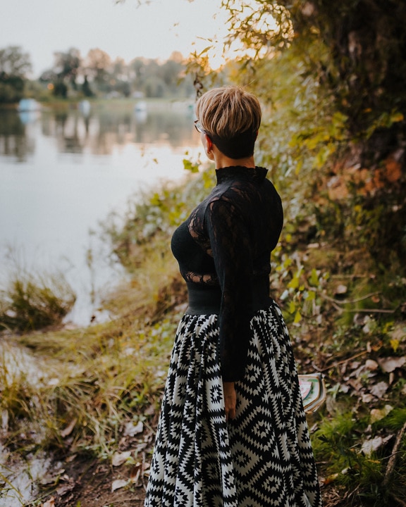 Woman in black and white dress on riverbank