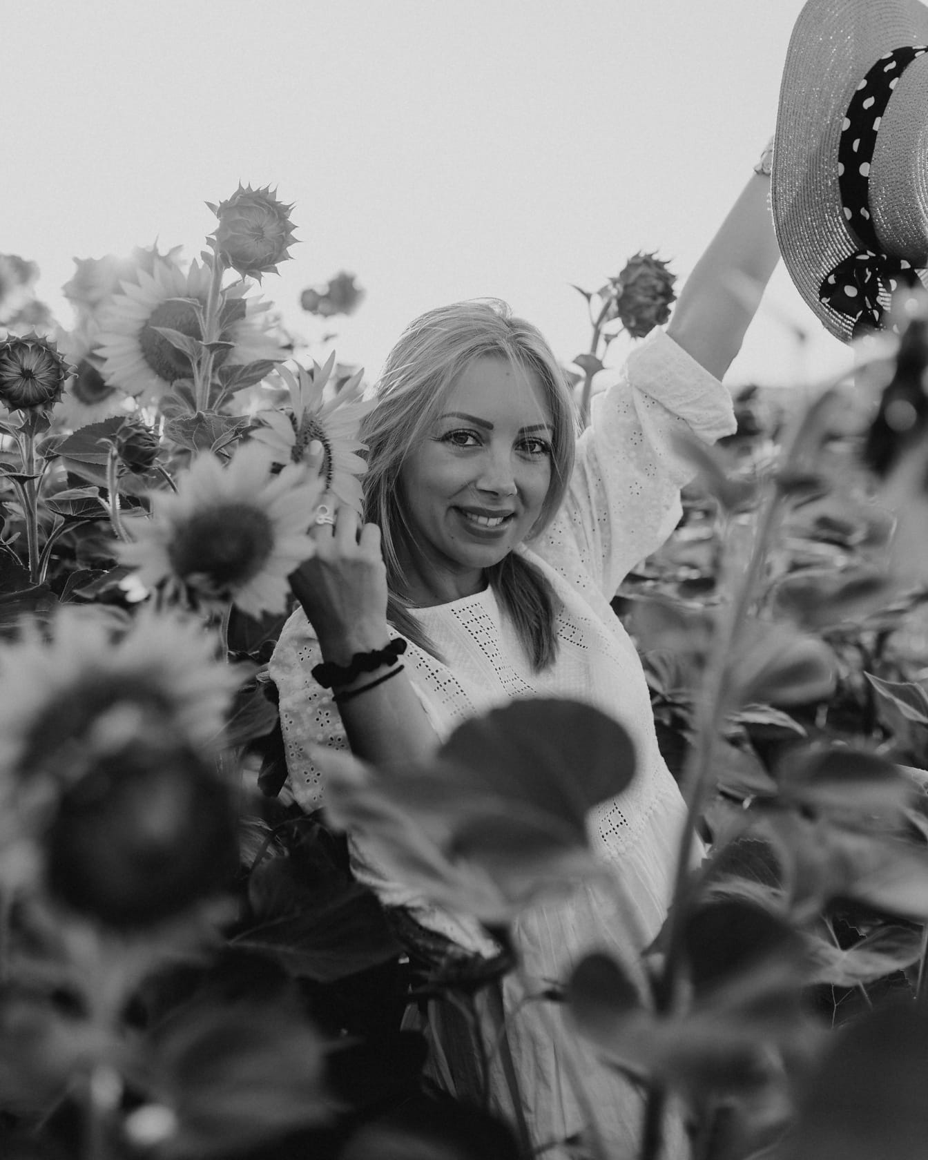 Portret monocrom al unei fete frumoase într-un câmp de floarea-soarelui