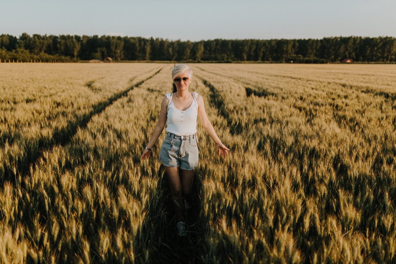 Blond hårkvinna bär avslappnad outfit i vetefält