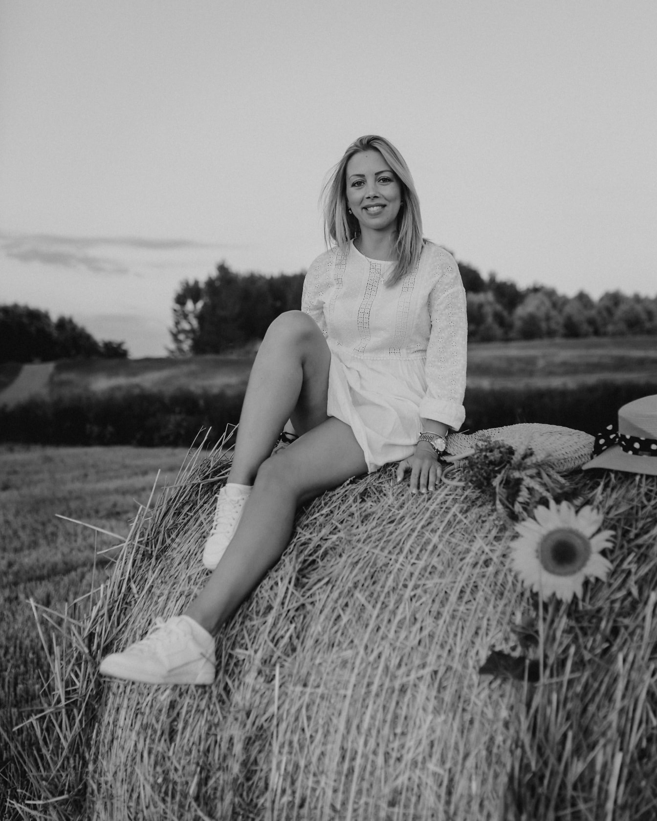 Очаровательная блондинка, сидящая на стоге сена, ролевая монохромная фотография