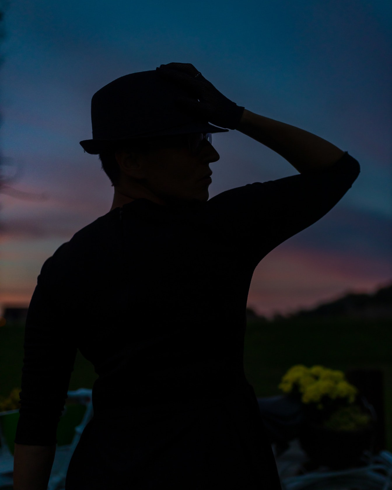 Silhouet van vrouw met hoed met de achtergrond van de schemerhemel