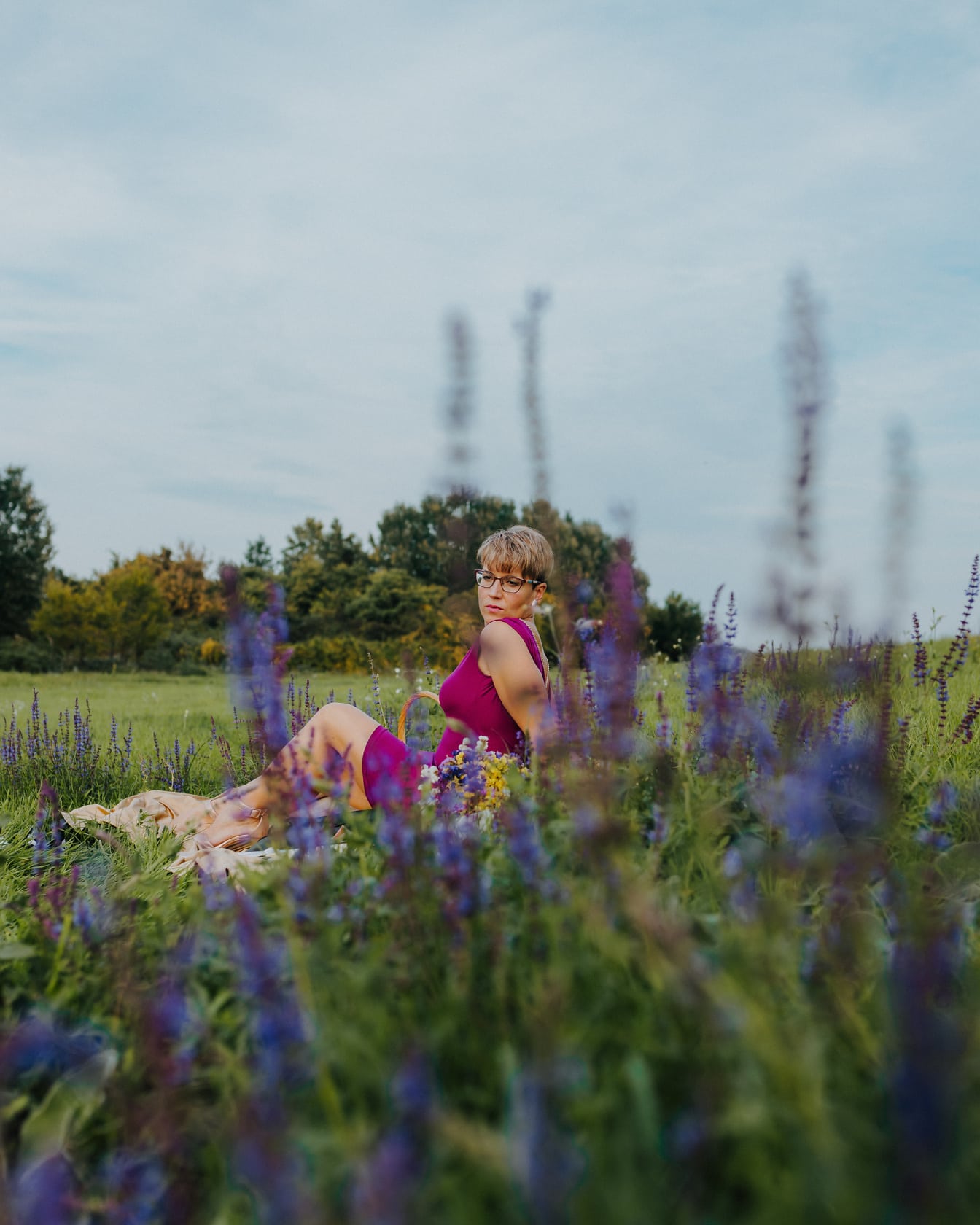 Hyvännäköinen nuori nainen istumassa niityllä
