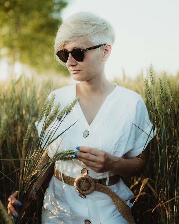 Rozkošná dáma s krátkými vlasy v bílých šatech v pšeničné barvě