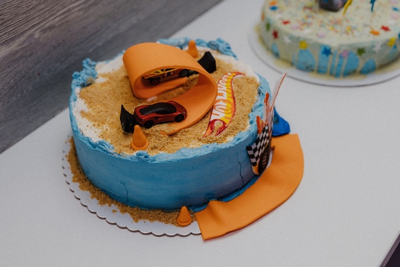 Orange yellow and dark blue birthday cake on kitchen table