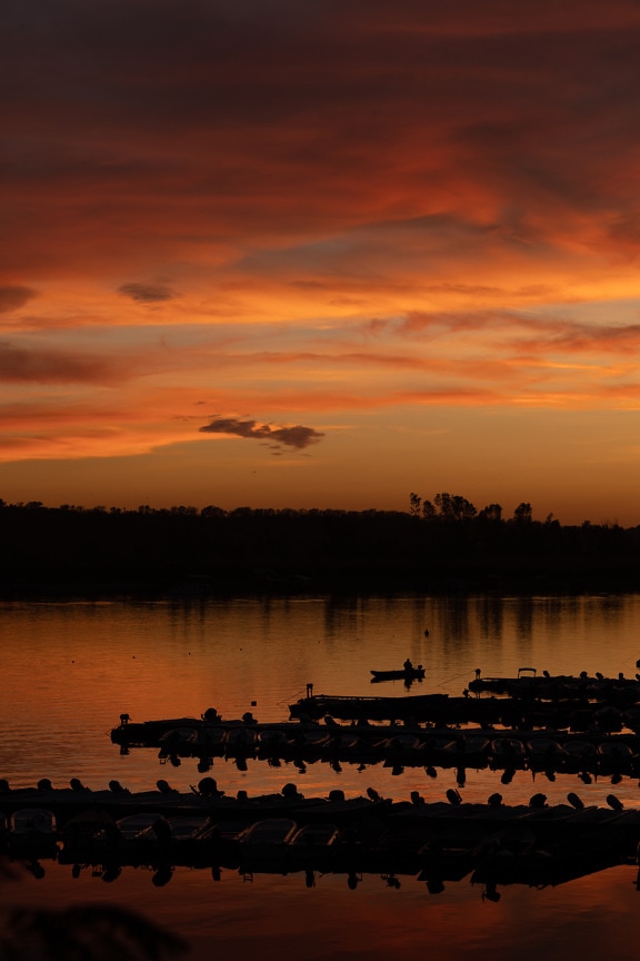 Tmavočervená a oranžovo žltá obloha východ slnka v prístave
