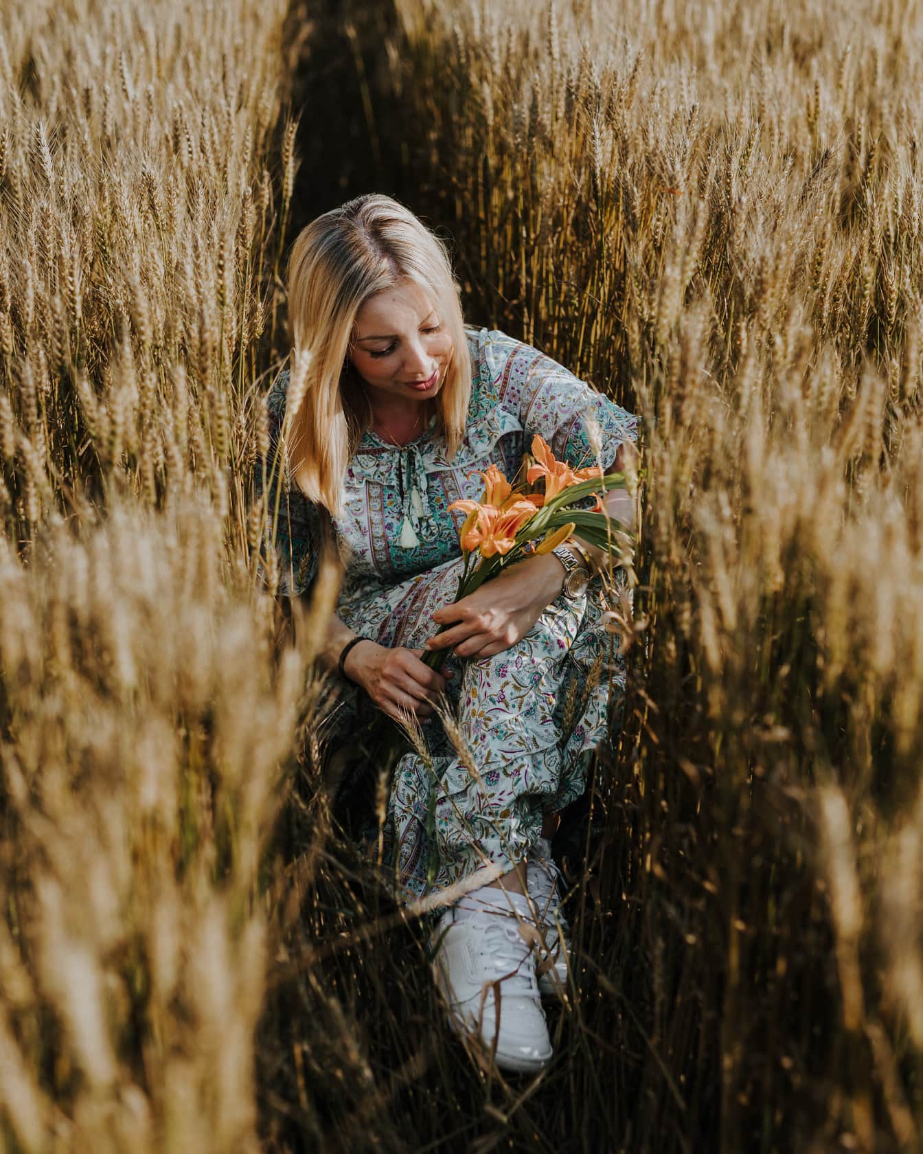 Dobre vyzerajúca blondínka s kvetmi amaryllis v pšeničnom poli
