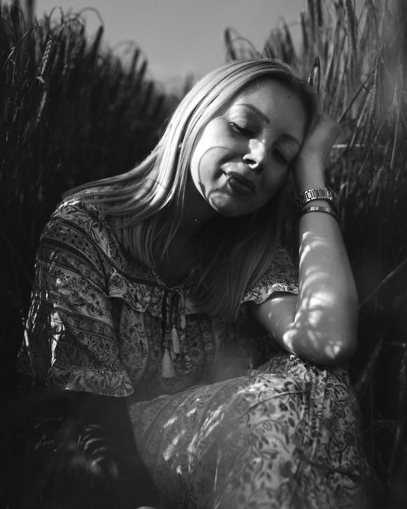 Szőke nő csukott szemmel ül a búzamezőn