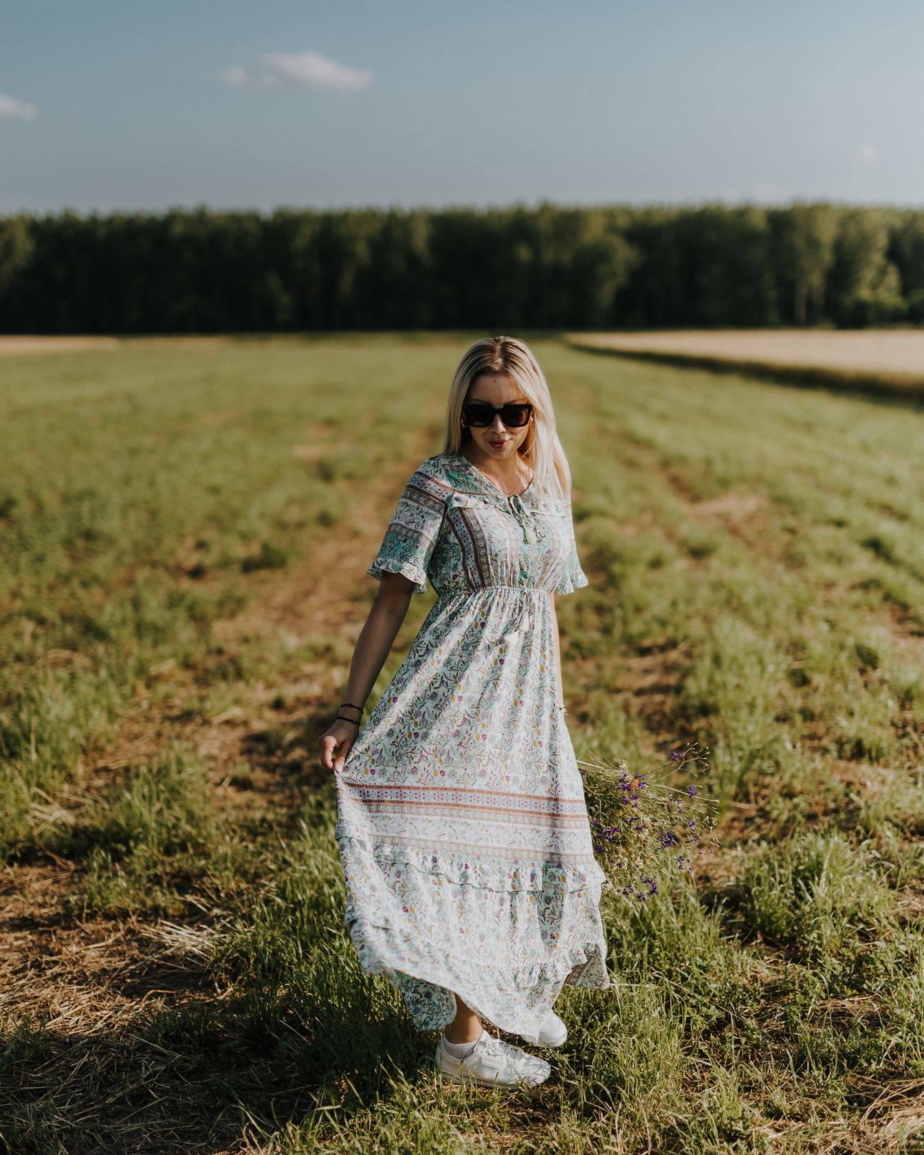 Junge Frau trägt ausgefallenes Blumenkleid-Outfit auf dem Feld