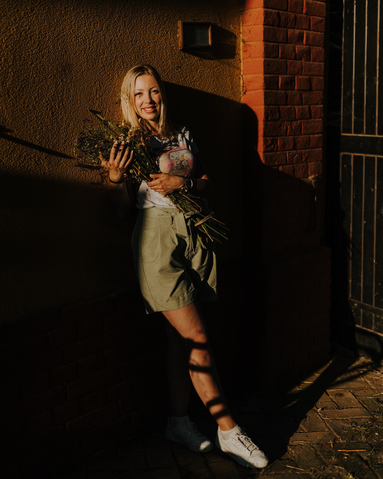 Портрет веселой блондинки в тени с букетом цветов