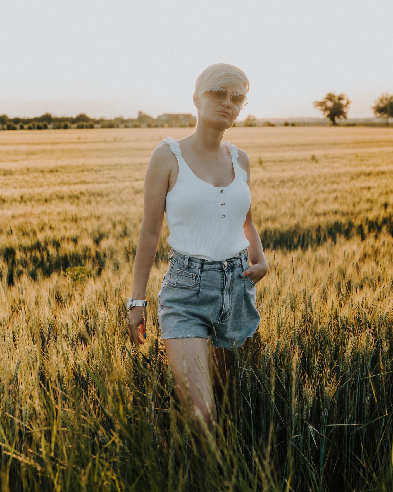 Cô gái tóc vàng ưa nhìn tạo dáng trong chiếc quần ngắn trên cánh đồng lúa mì