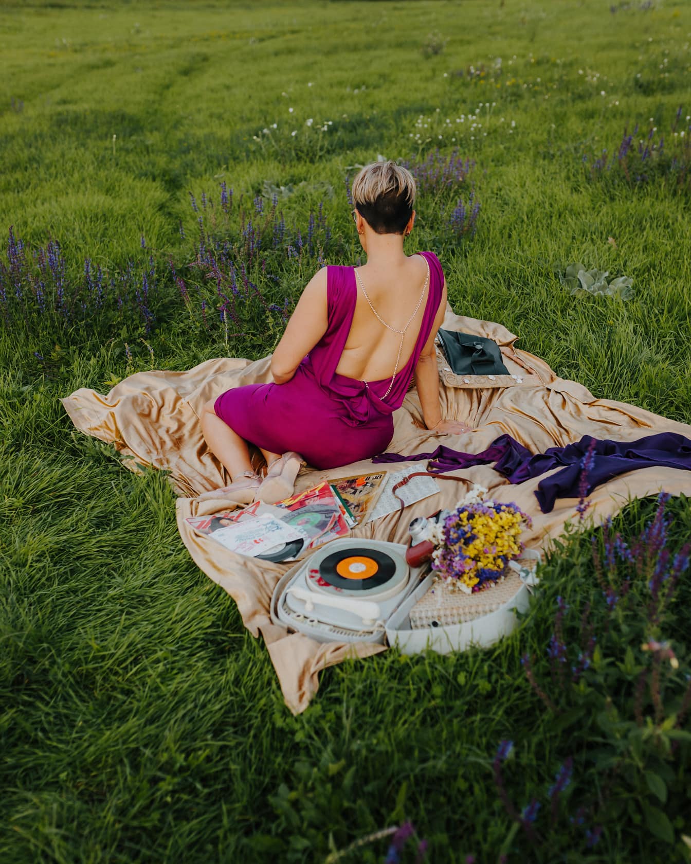 Upea nainen poseeraa tyylikkäässä violetissa mekossa piknikviltillä