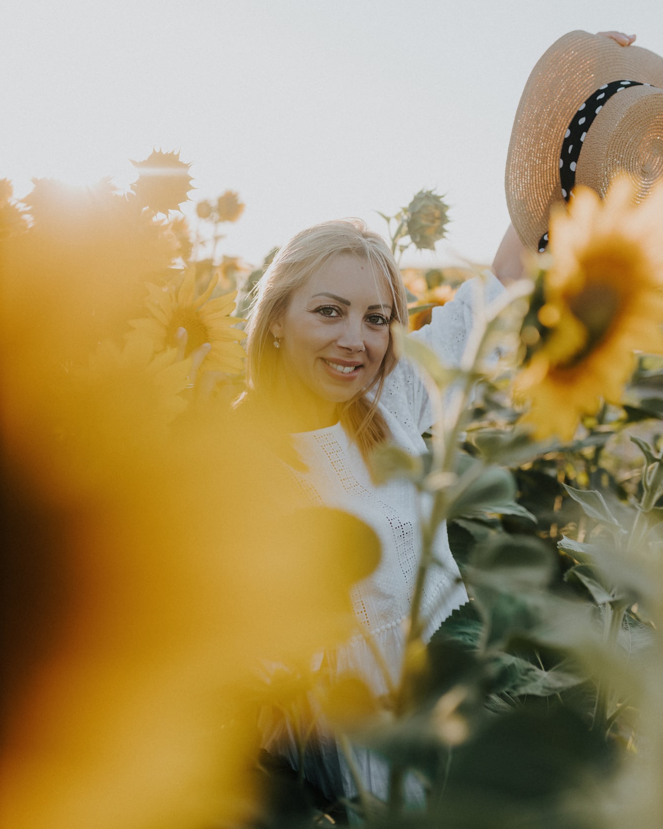 De vrij vrolijke vrouw van het blondehaar op zonnebloemengebied bij de zomerseizoen