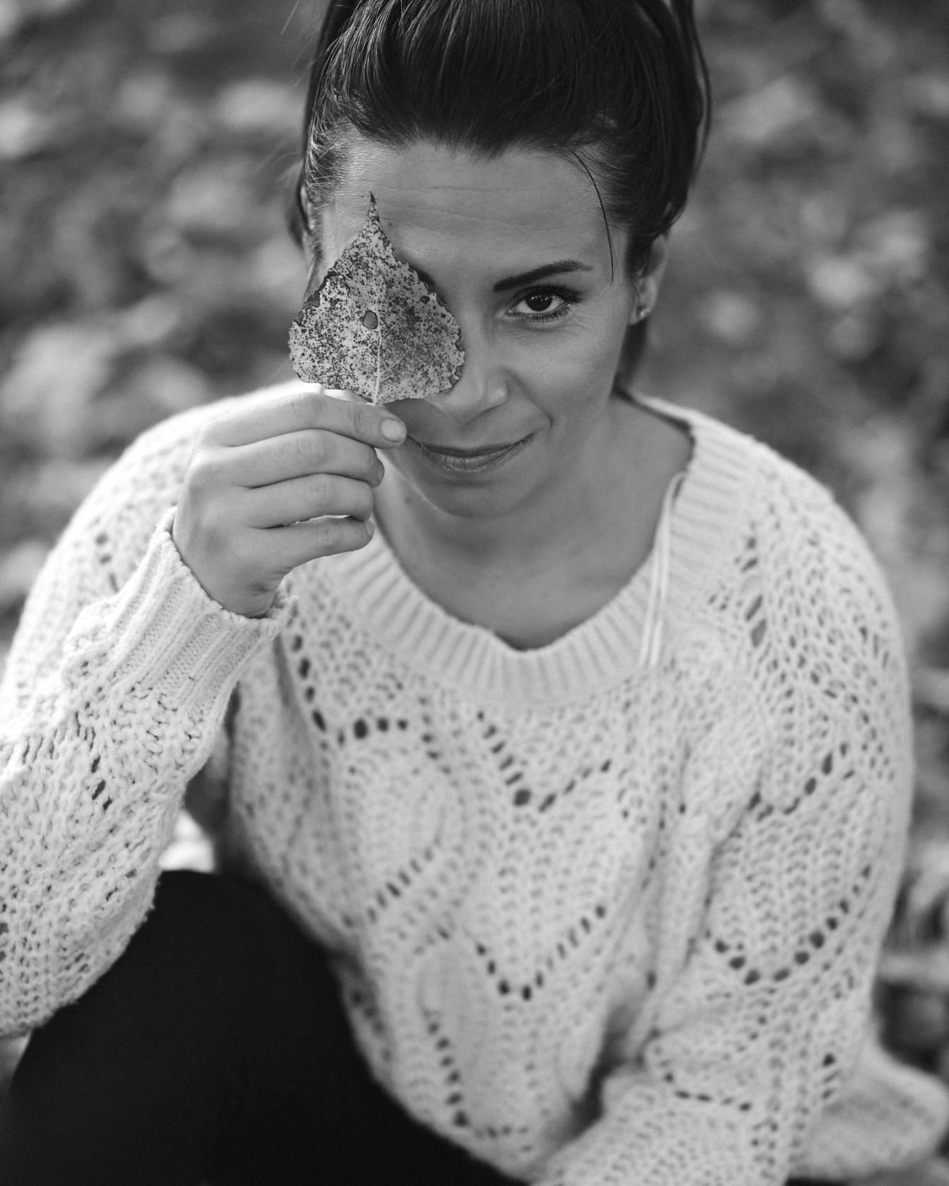 Woman holding leaf on face monochrome portrait