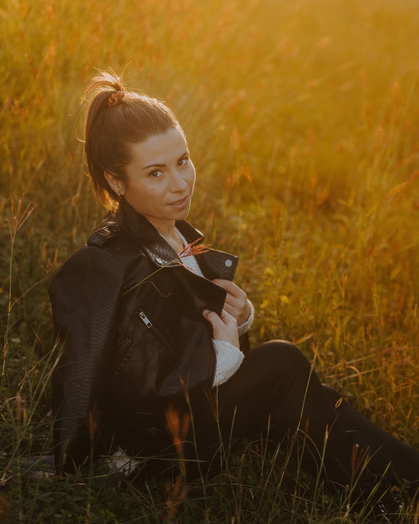 Portret prekrasne brinete s kožnom jaknom s pozadinom sunčeve svjetlosti