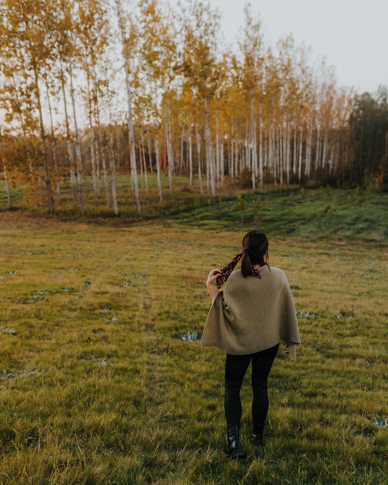 Brunette kvinne bærer poncho i åssiden om høsten