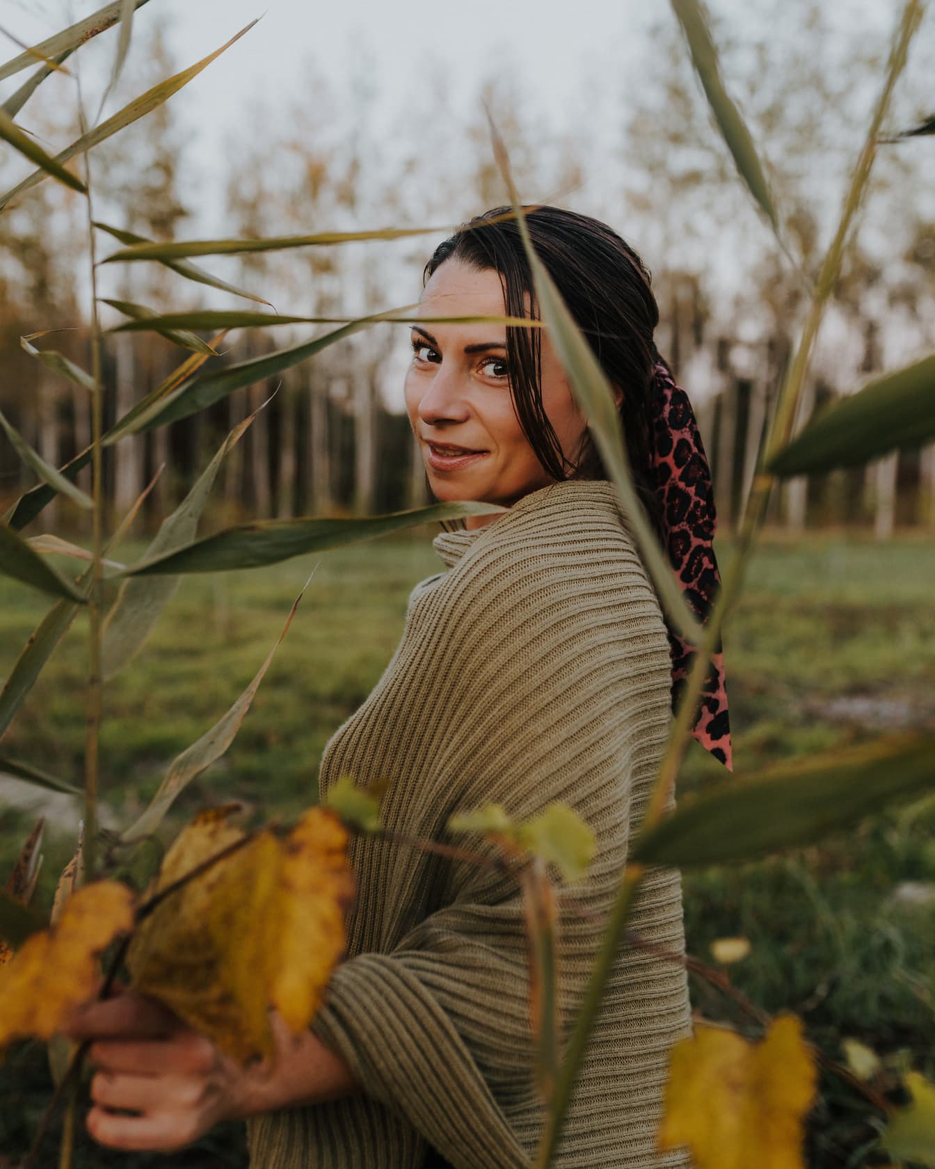 Cô gái tóc nâu xinh đẹp tạo dáng trong chiếc áo len ở vùng đầm lầy