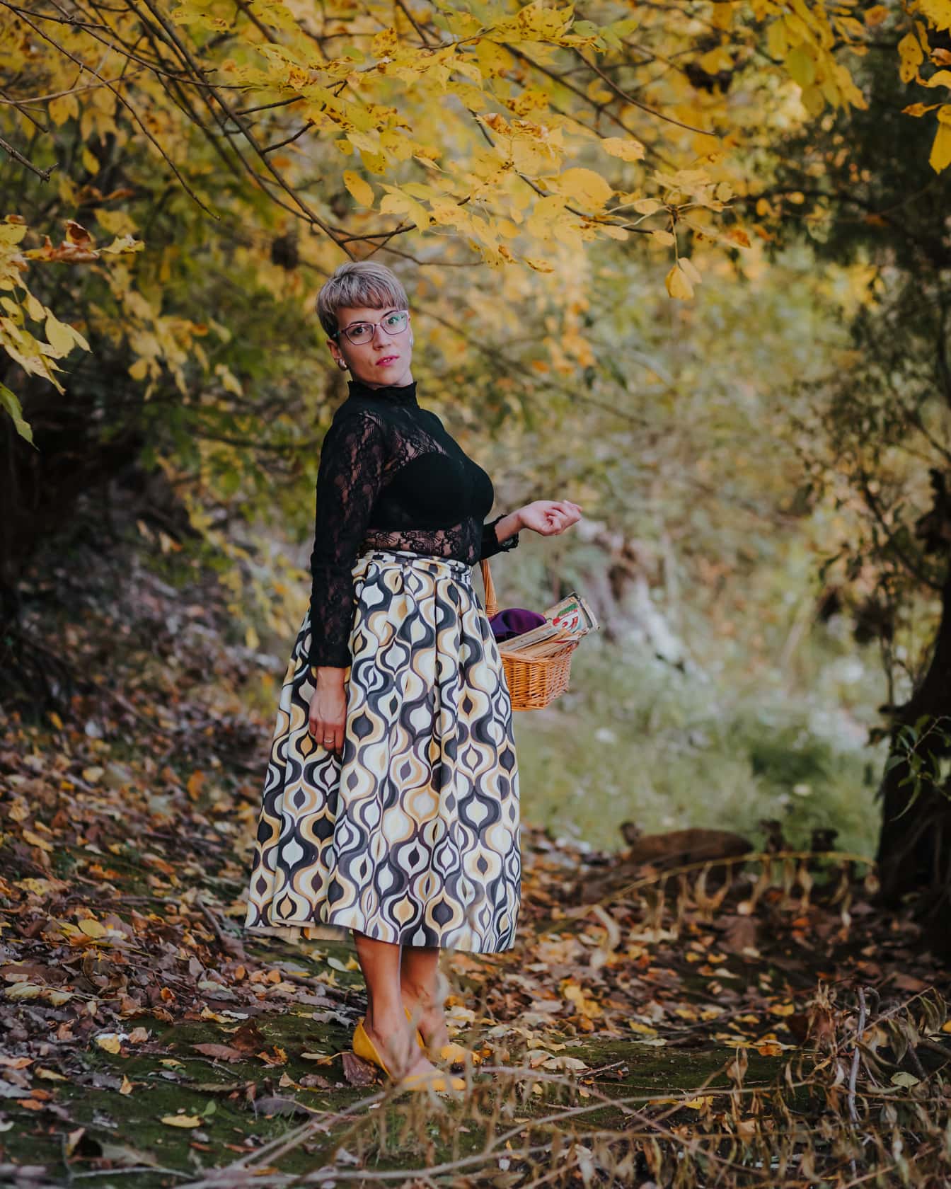 Bonita dama con cesta de mimbre en el bosque de otoño