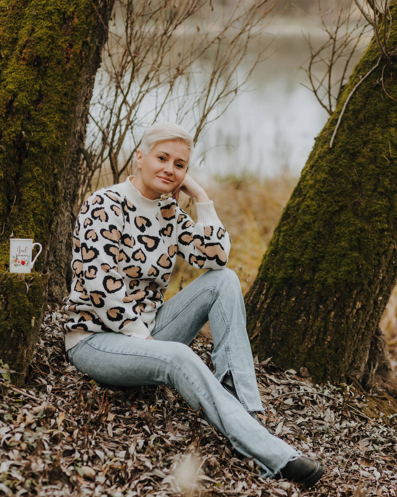 Hyvännäköinen lyhythiuksinen blondi villapaidassa ulkona istuen