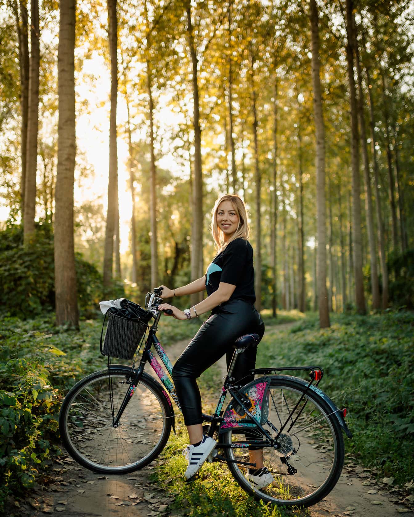 Blondă frumoasă pe bicicletă pe drum forestier