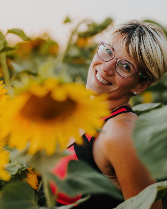 Gorgeous blonde hair woman smiling in sunflowers field