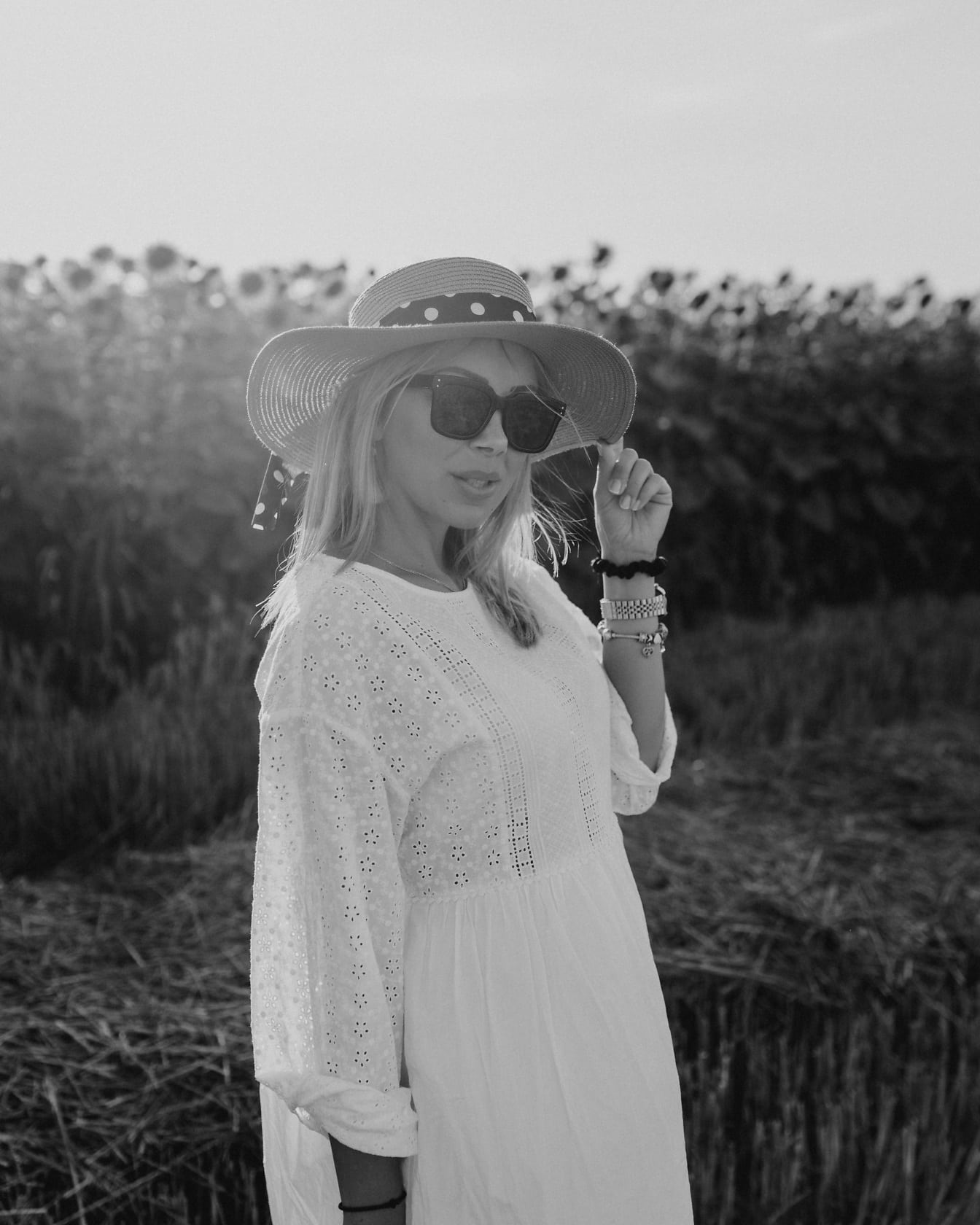 Ładna blondynka w słomkowym kapeluszu i okularach przeciwsłonecznych w słoneczny dzień