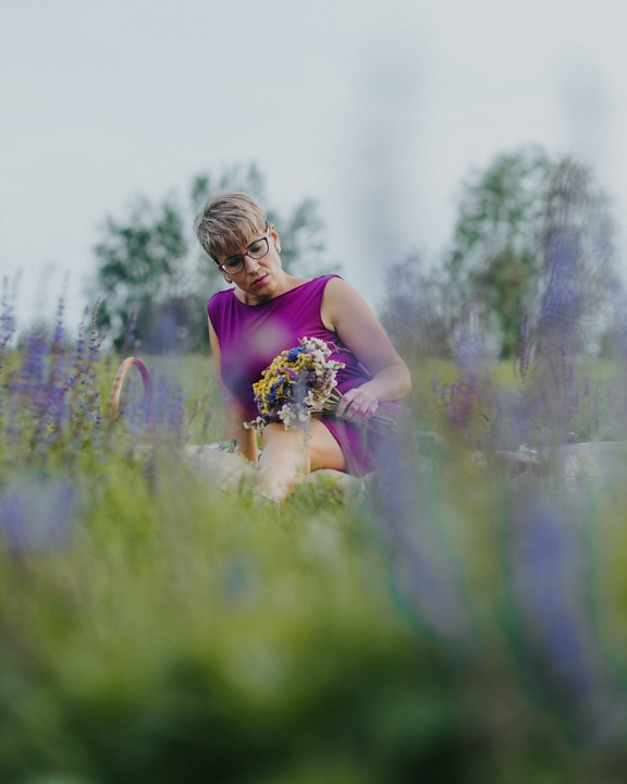 Pretty lady in purple dress laying on meadow