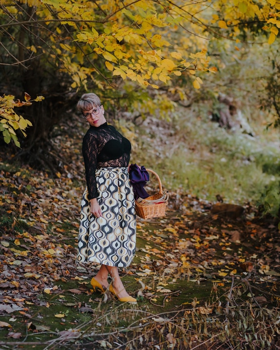 Hübsche Dame trägt schickes schwarz-weißes Outfit im Herbstwald
