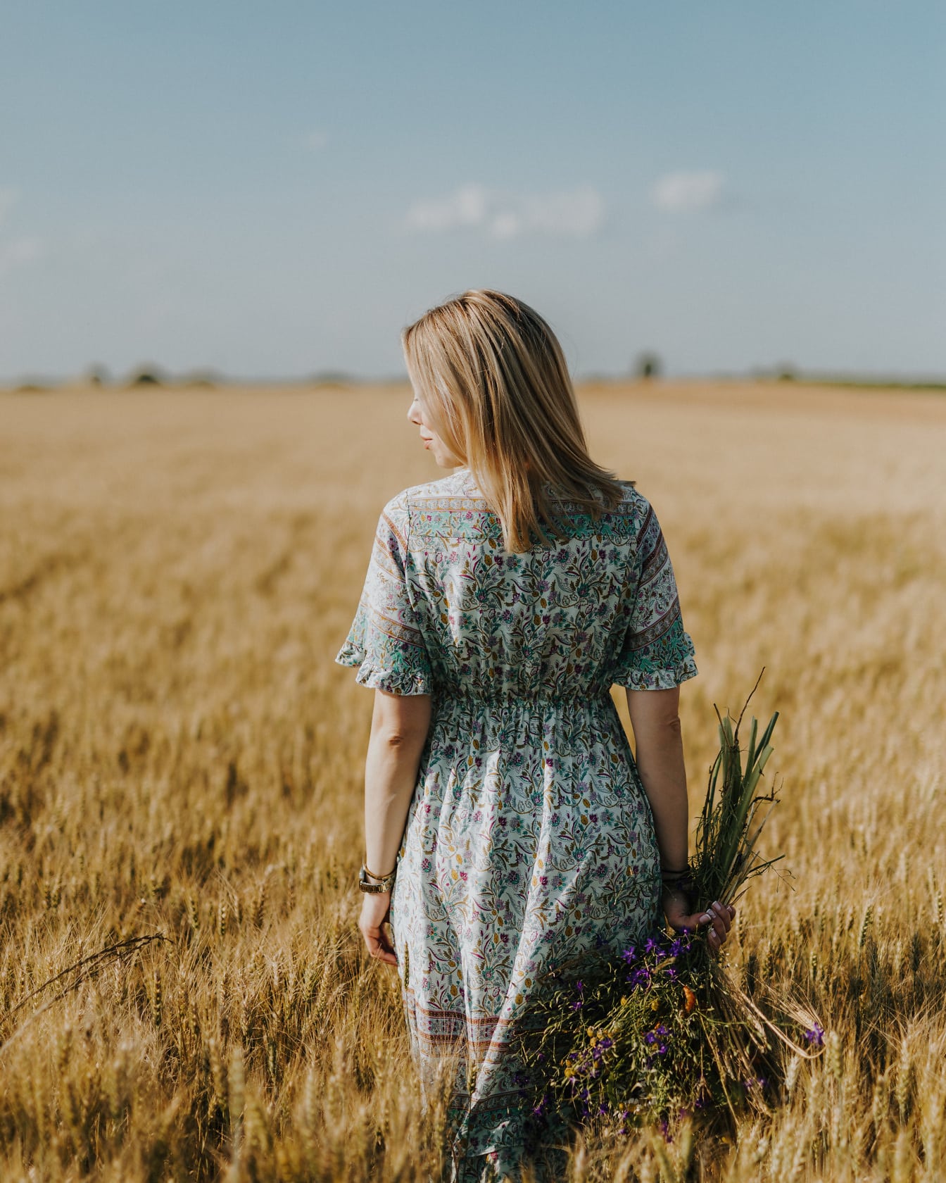 Blondynka w tradycyjnym rustykalnym stroju pozuje na polu pszenicy