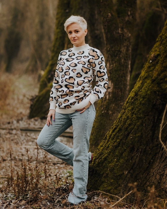 Blonde Frau posiert in Pullover und Jeanshose