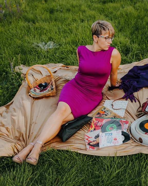 Splendida modella fotografica in posa su un picnic in abito viola