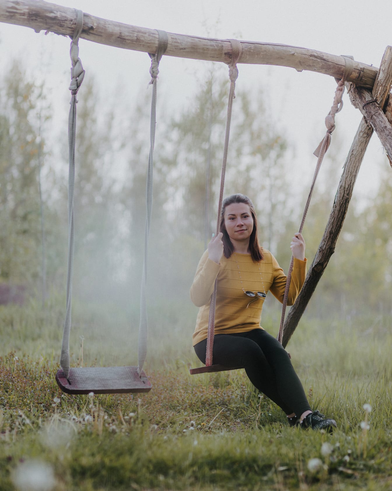 Smuk kvinde sidder på gammel træ rustik gynge