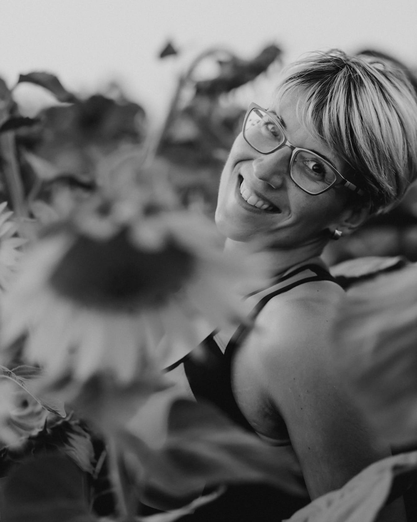 Zwart-wit portret van vrolijke vrouw in zonnebloemen