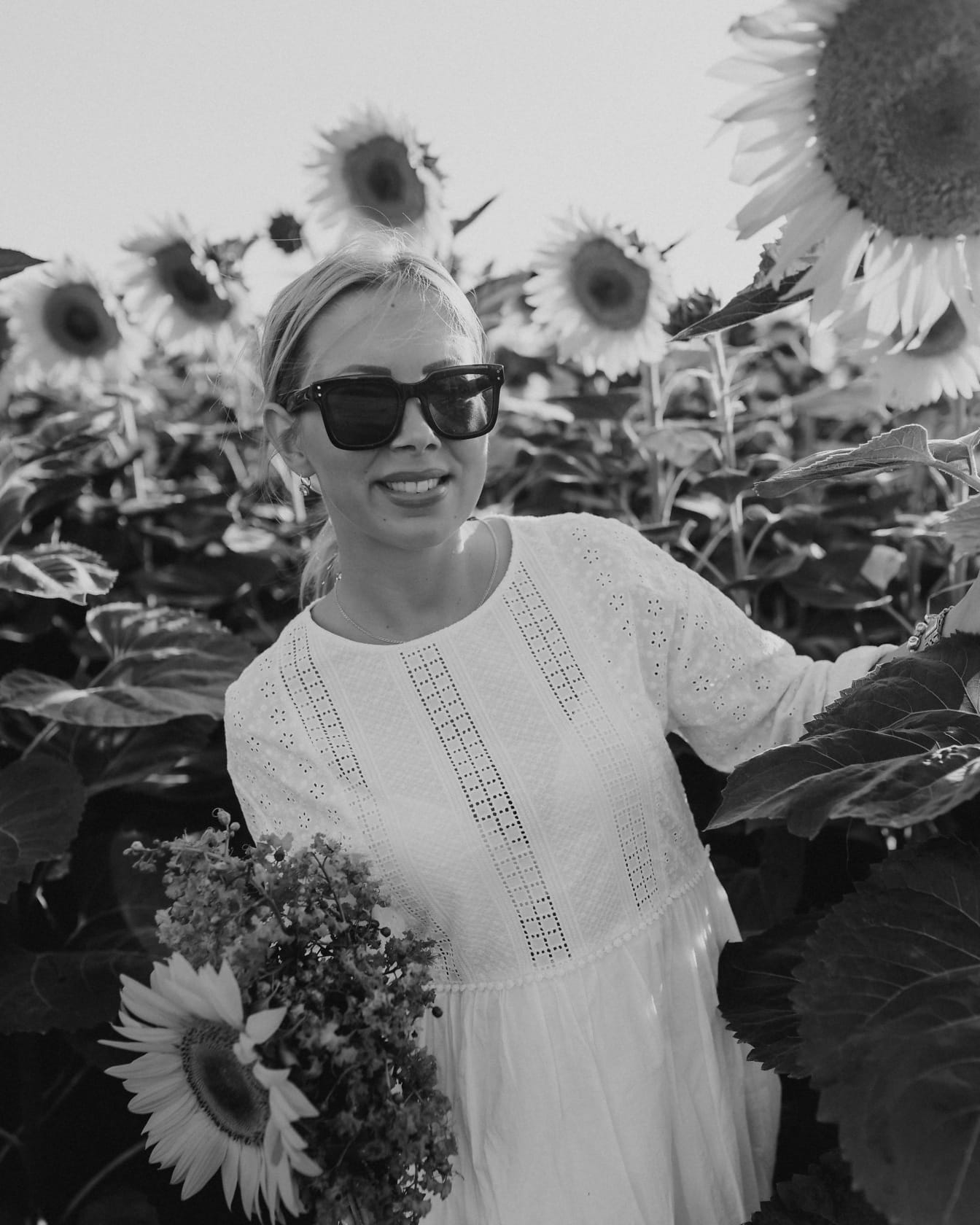 Portrait of pretty blonde with sunglasses in sunflowers